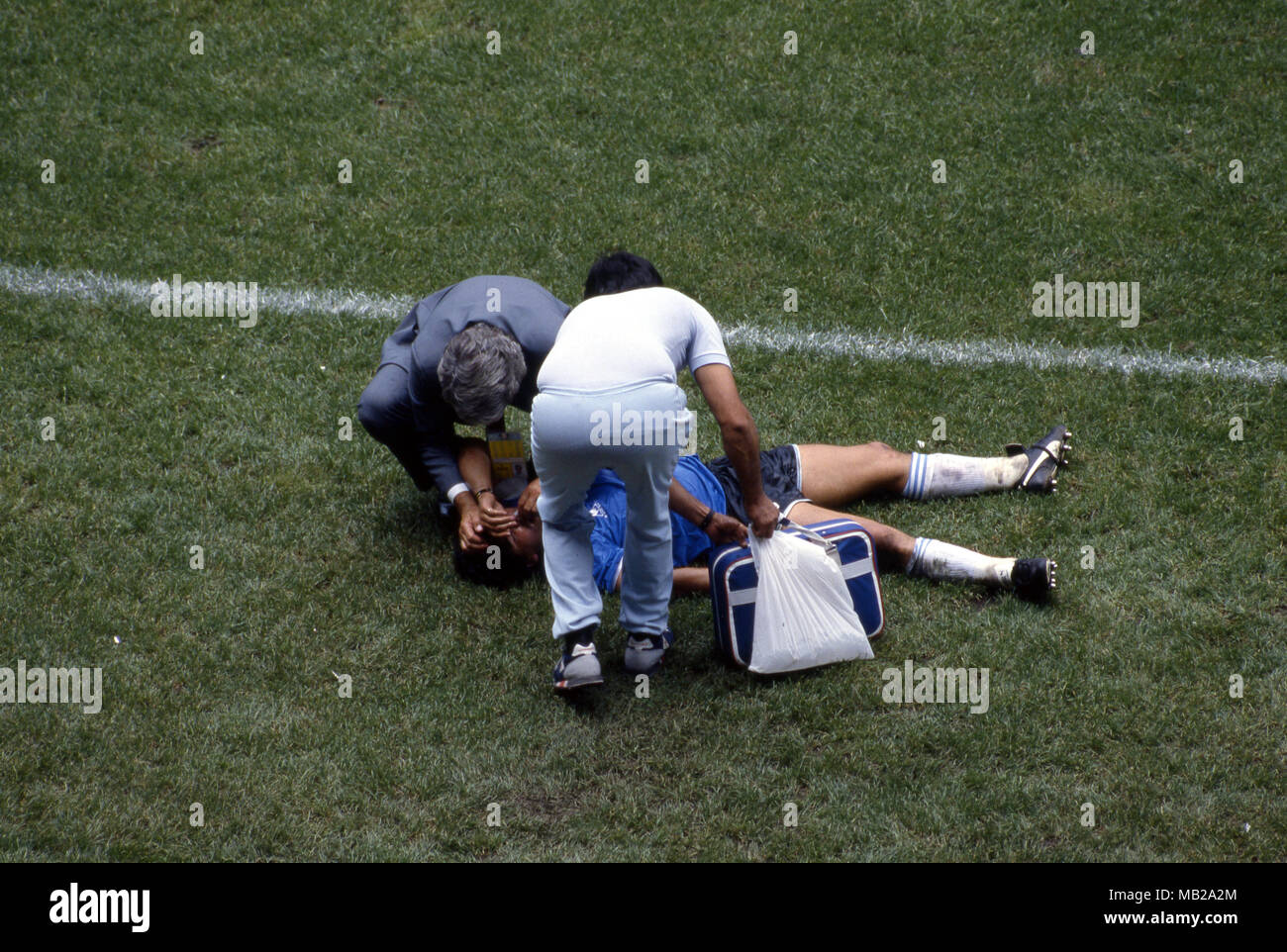 FIFA WM - Mexiko 1986 22.6.1986, Estadio Azteca, Mexico, D.F. Viertelfinale Argentina v England. Diego Maradona (Argentinien), die auf dem Gras mit einer blutigen Nase, der Umgang mit ihm ist der Arzt des Teams Ra Madero. Stockfoto