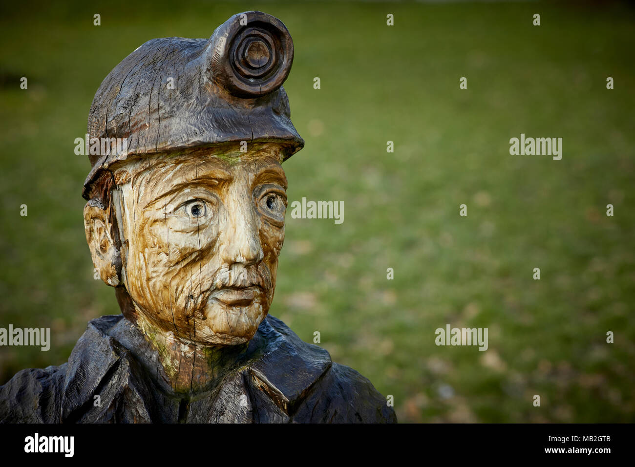 Geschichte des Bergbaus Mosley gemeinsamen Dorf in der Nähe von Leigh, Kettensäge Bildhauer Andy Burgess Miner Büste Skulptur von kranken Baum im Village Green mehr Manc Stockfoto