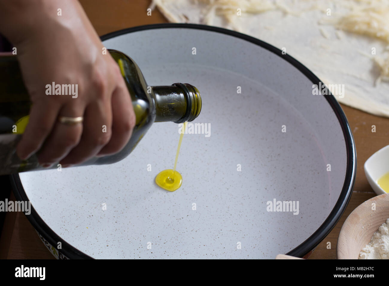 Gießen Olivenöl auf Metallplatte Stockfoto