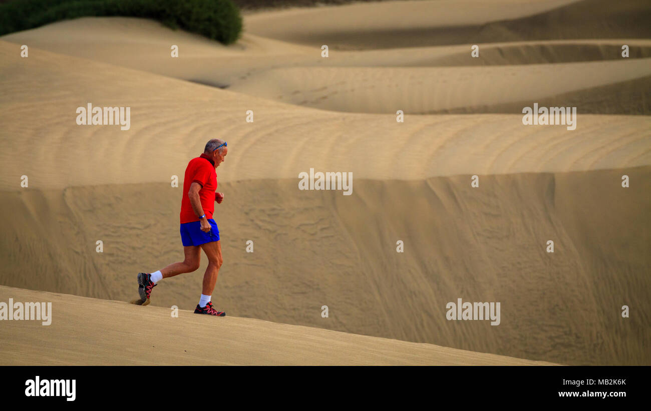 Ältere Mann läuft durch die Maspalomas Wüste. Stockfoto