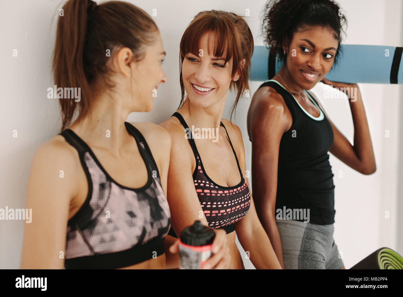 Weibliche Freunde in der Turnhalle plaudern nach dem Training Session. Gemischten Rennen junge Frauen entspannen Sie im Fitnessraum nach dem Training im Fitness Studio. Stockfoto