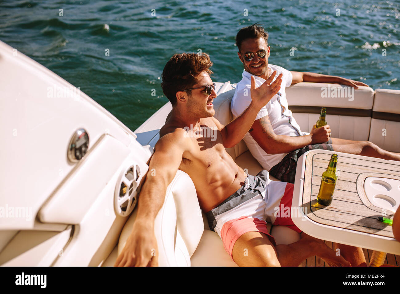 Junge Männer in einem Boot sitzen und in Partei. Männliche Freunde Party in einer Yacht. Stockfoto