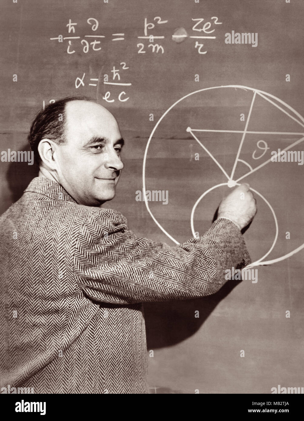 Enrico Fermi (1901-1954), italienisch-amerikanische Physiker und Pionier der Kernspaltung, zeigt eine Physik Gleichung auf einer Schiefertafel, c 1950. Fermi arbeitete auf dem Manhattan Projekt während des Zweiten Weltkrieges und wichtige Beiträge für die Entwicklung der Quantentheorie, Kern- und Teilchenphysik und Statistische Mechanik. Stockfoto