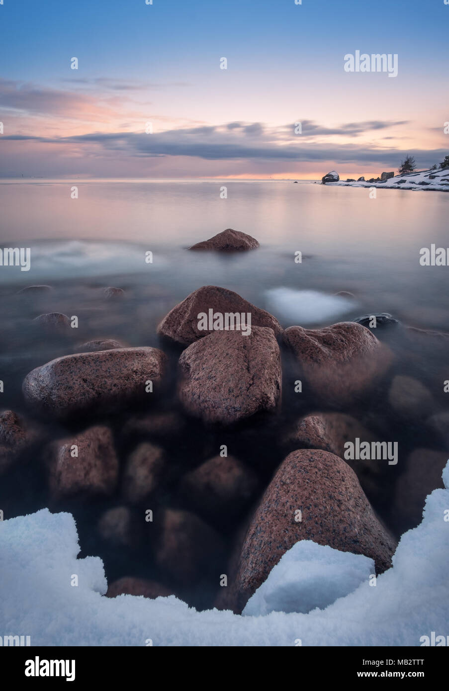 Die malerische Landschaft mit Meer und Strand mit Steinen nach Sonnenuntergang in Finnland Stockfoto