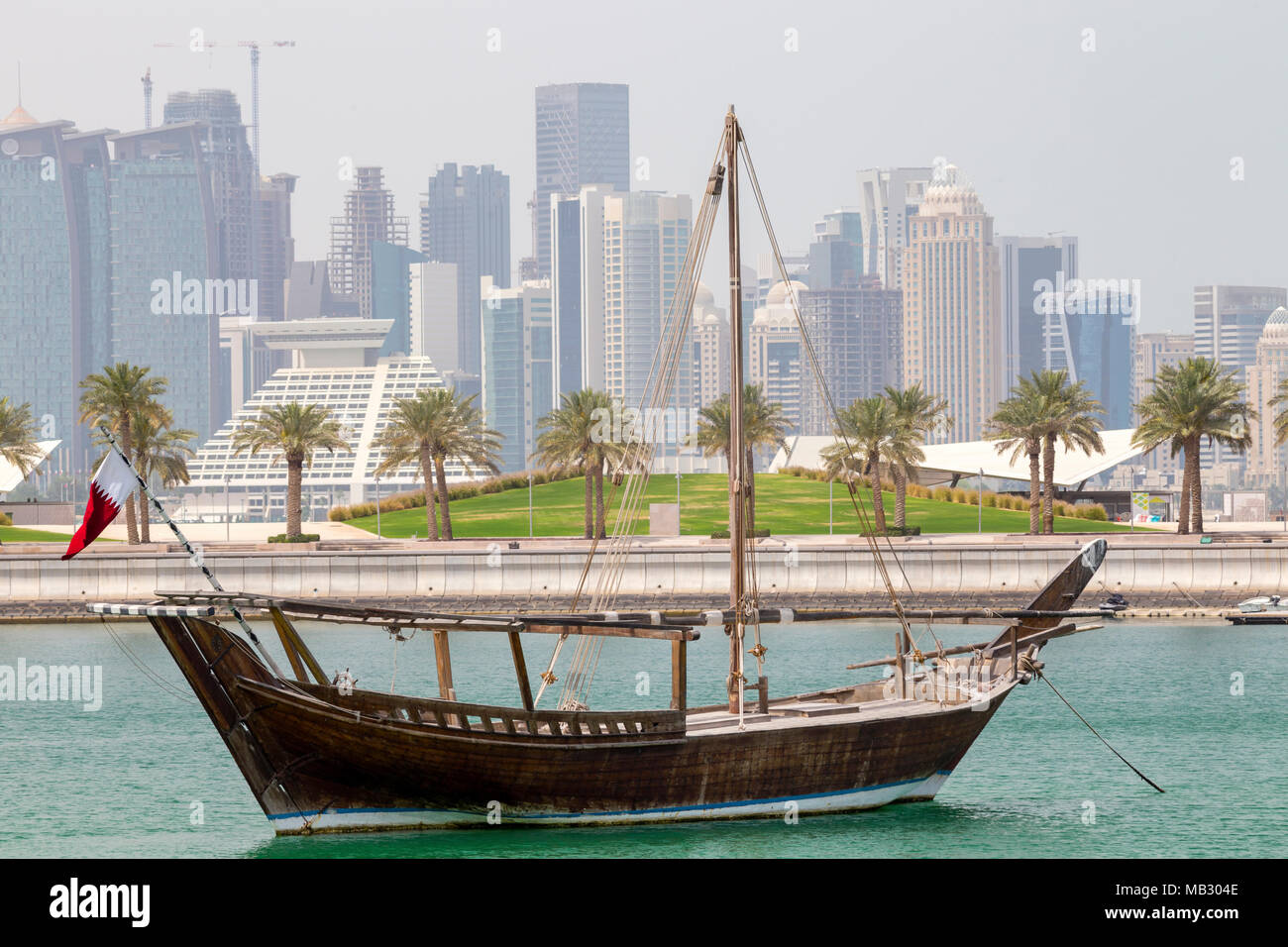 DOHA, Katar - 5. April 2018: einer traditionellen Dhau in das Museum für Islamische Kunst Park festgemacht, mit Wolkenkratzern von Doha City hinter sich. Stockfoto