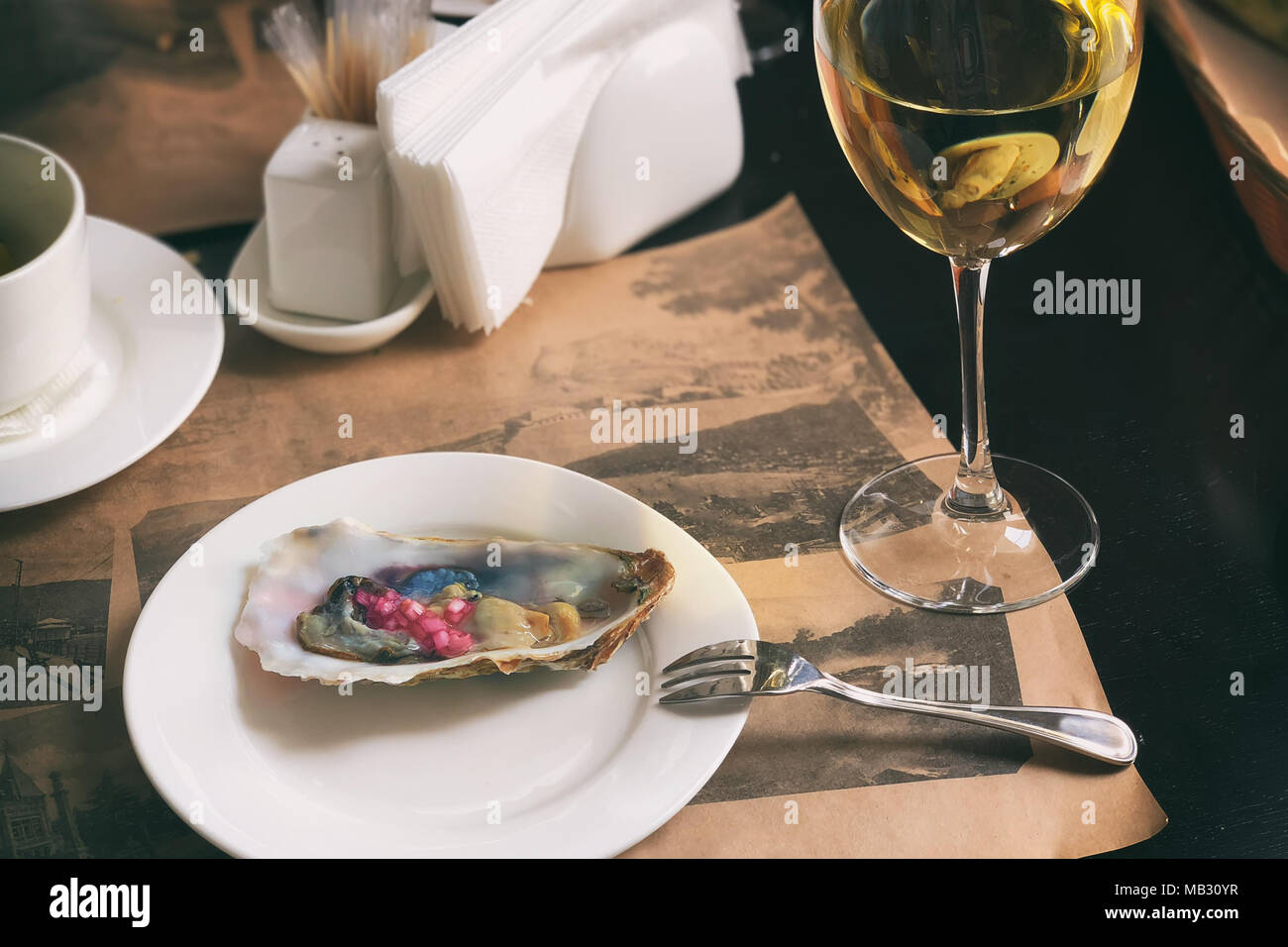 Ein weißer Teller mit leckeren Austern mit rotem Krim Zwiebeln und weißen Wein serviert. Serviert werden. Ein horizontaler Rahmen. Stockfoto