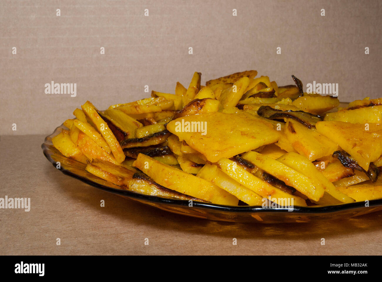 Gebratene Kartoffeln, gewürzt mit Kurkuma, auf einer Platte liegen. Ein heisses Land Mahlzeit. Stockfoto