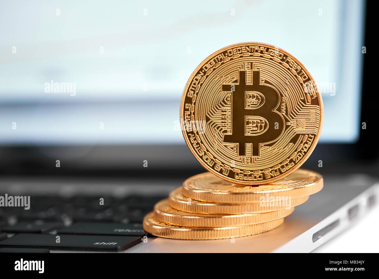 Stapel von Golden bitcoins mit einem bitcoin an der Kante stehend auf Silber Laptop. Cryptocurrency virtuelle digitale Geld web elektronische Währung blockchain zukünftige Trends verschwommenen Hintergrund Stockfoto