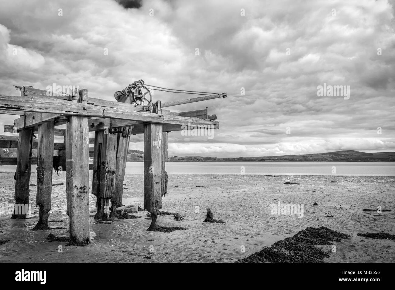 Ein schwarz-weiß Bild von einer alten hölzernen Pier bei Ebbe. Stockfoto