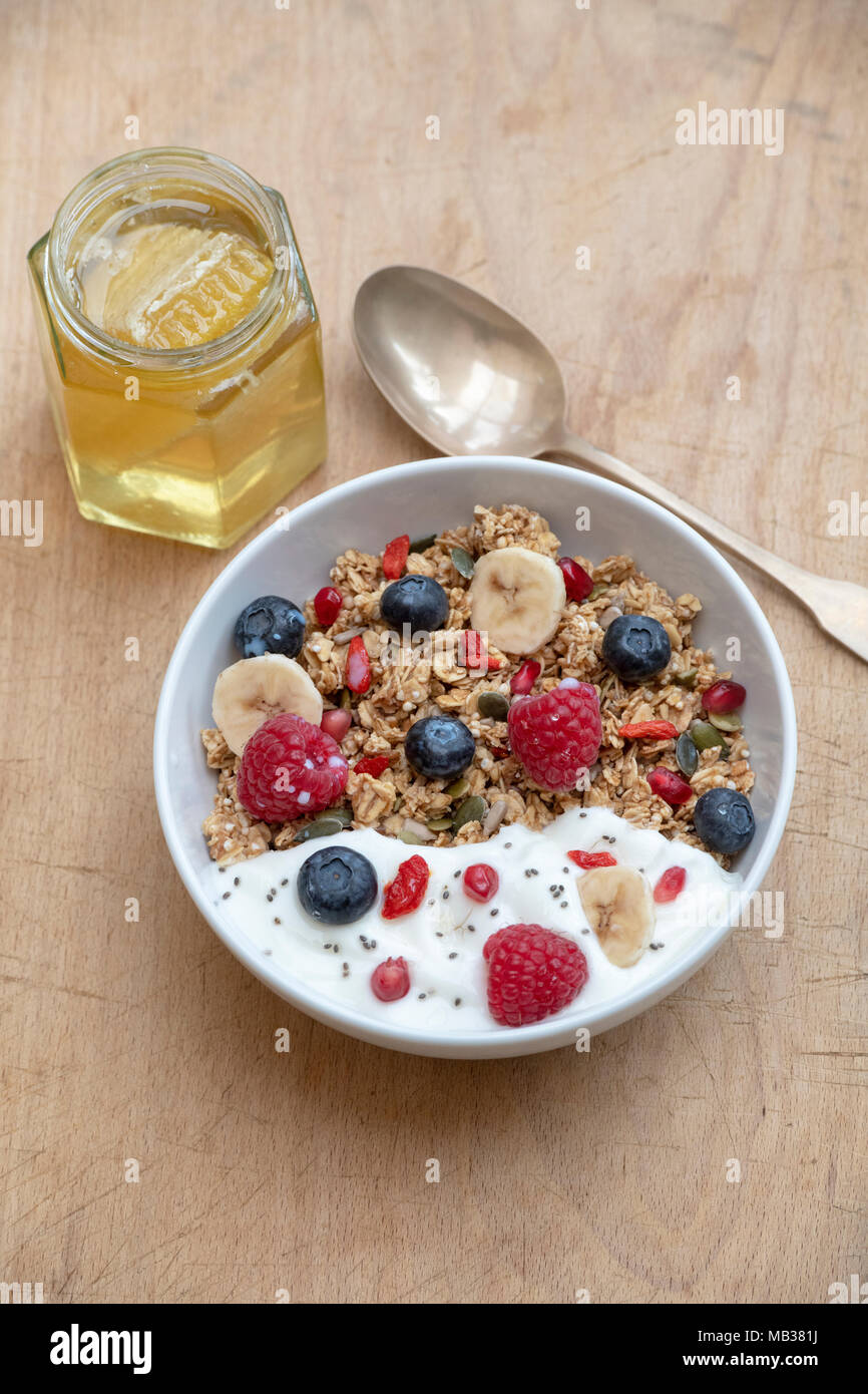Frühstück Schüssel Müsli, Früchte, Samen, Joghurt und Honig auf einem Holz Hintergrund Stockfoto