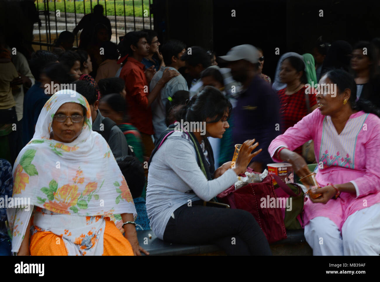 Zwei Damen vertieft im Gespräch trotz aller, Chaos im Hintergrund, die Chhatrapati Shivaji Terminus, Mumbai, Indien. Stockfoto