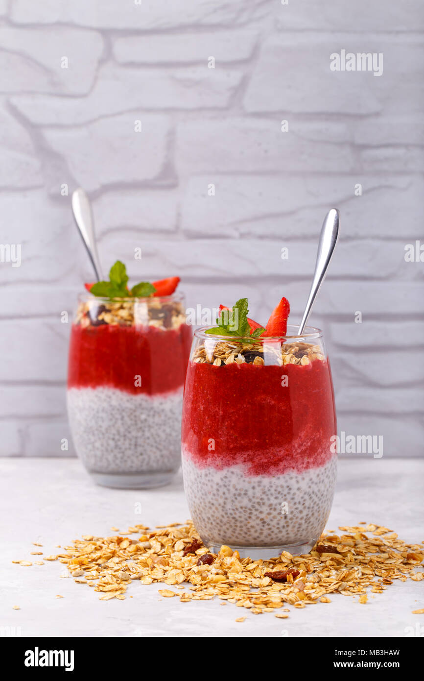 Gesunde Chia, Kokos, Erdbeere Pudding mit hausgemachtem Müsli auf weissem Holztisch Stockfoto
