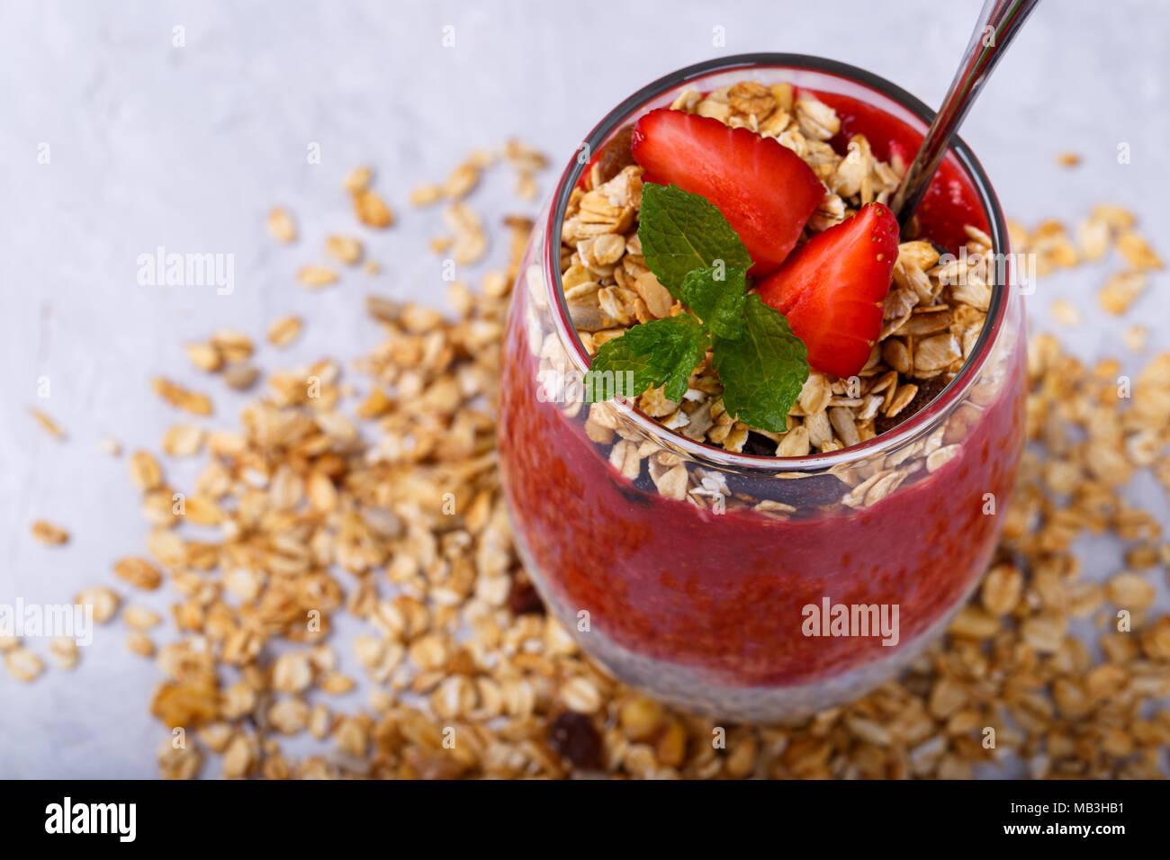 Gesunde Chia, Kokos, Erdbeere Pudding mit hausgemachtem Müsli auf weissem Holztisch Stockfoto