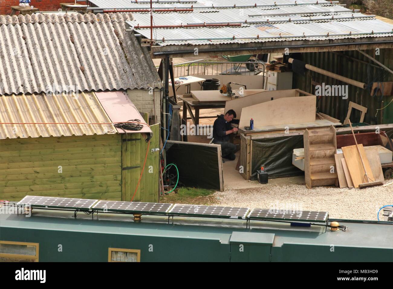 Weißer Mann tragen Overalls arbeiten in trockenen Werft Reparatur Kanal Boot an heyford Wharf, Oxfordshire, UK Stockfoto