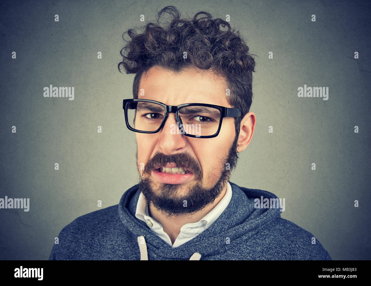 Angewidert Mensch empfindet Abneigung gegen etwas, Stirnrunzeln im Gesicht, an der Wand Hintergrund isoliert. Emotionale junger Erwachsener Stockfoto