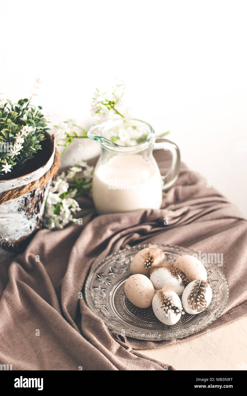 Schönen Pastelltönen Eier mit Federn auf eine weiße Holztisch und Frühlingsblumen Stockfoto