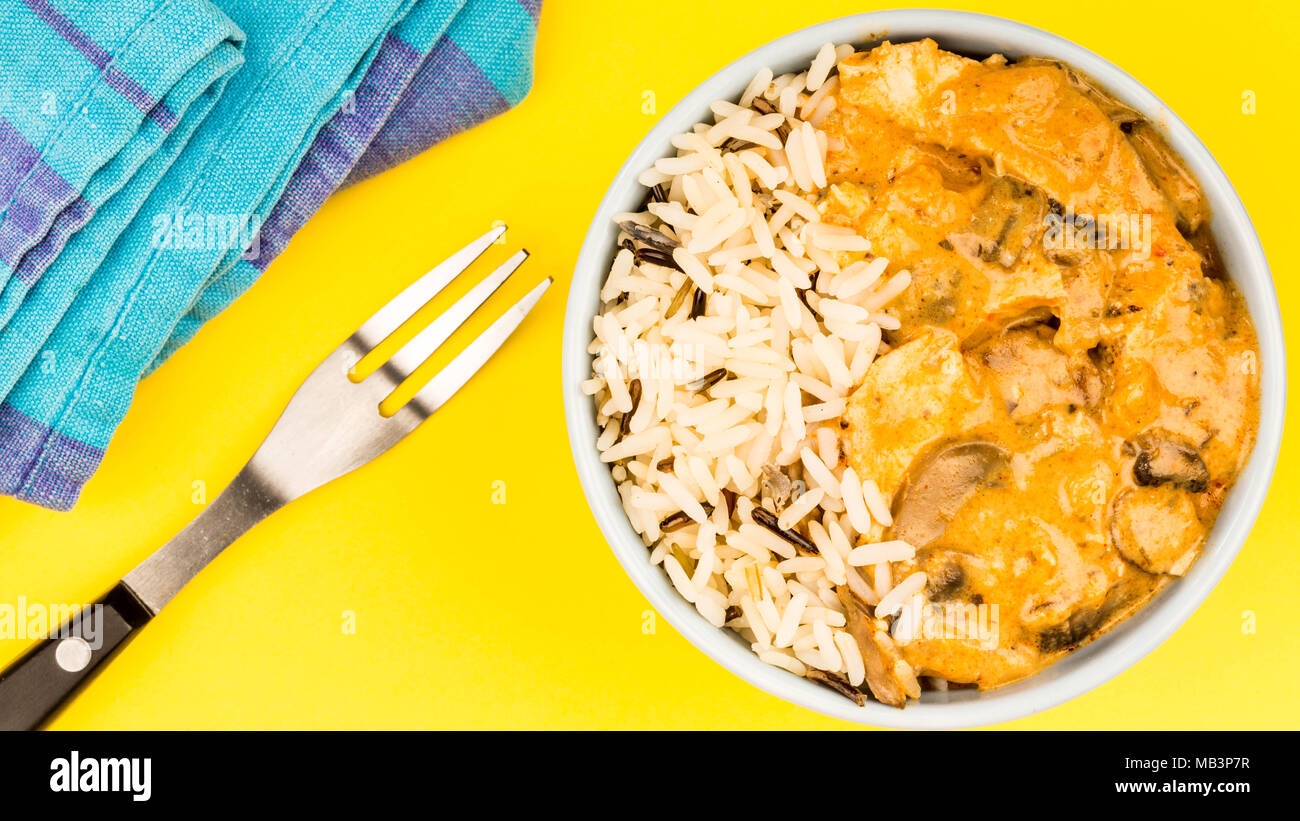 Huhn und Pilz Stroganoff mit Reis auf gelbem Hintergrund Stockfoto