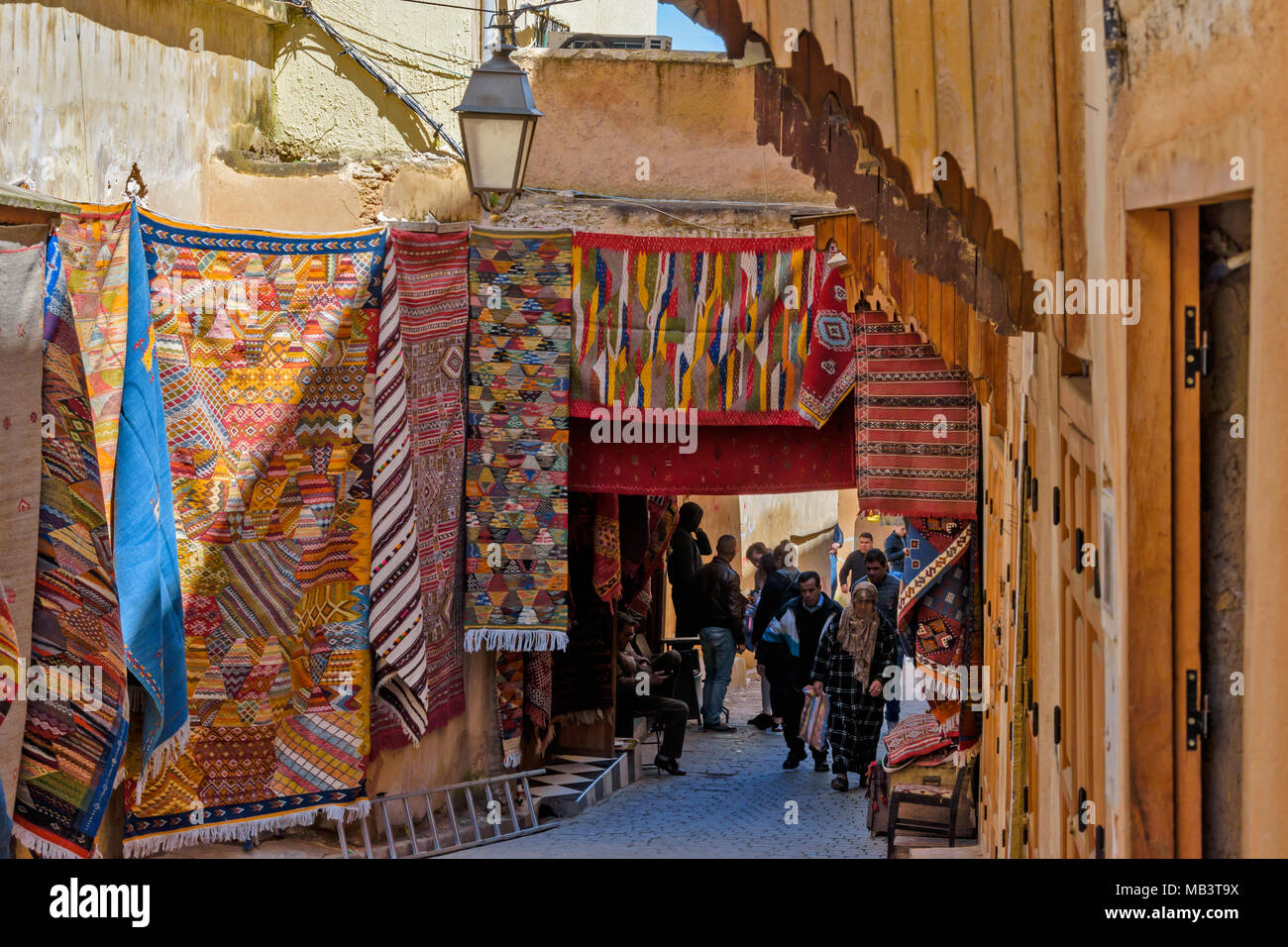 Marokko Fes Medina Souk IN DER MEDINA TEPPICHE KILLIMS AUF DER ANZEIGE UND DER TEPPICH VERKÄUFER UNTER DEM BOGEN Stockfoto