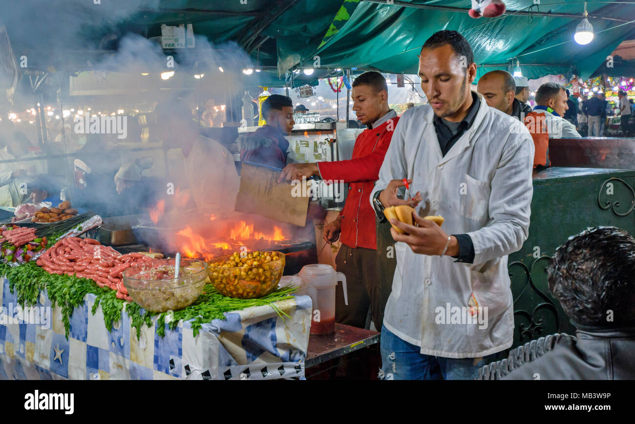 Marokko Marrakesch Djemaa el Fna MEDINA SOUK AM ABEND AUF DEM PLATZ STÄNDEN EINE VIELZAHL VON gekochten Lebensmitteln, WO SIE SITZEN UND ESSEN PLUS FLAMMEN Stockfoto