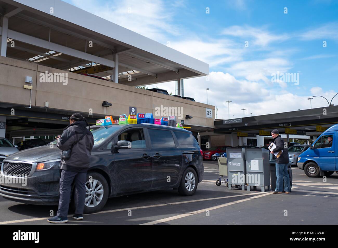 Mietwagen zurück Agenten stand mit einem Auto, das in einer großen Anzahl von Kunststoff status Kennzeichnung Kegel, am Newark International Airport in Newark, New Jersey, 16. März 2018 besprochen wurde. () Stockfoto