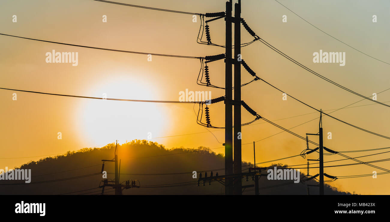 Hochspannung Strommasten und Leitungen (Silhouette) mit Sonnenuntergang im Hintergrund. Low Key, in der Nähe. Natürliche (Sonne) und industrielle Quellen von Energie zusammen Stockfoto