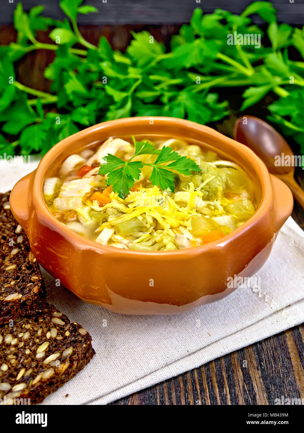 Minestrone mit Fleisch, Sellerie, Tomaten, Zucchini, Kohl, Erbsen, Karotten und Pasta in einem irdenen Schüssel auf eine Serviette, Käse und Brot Stockfoto