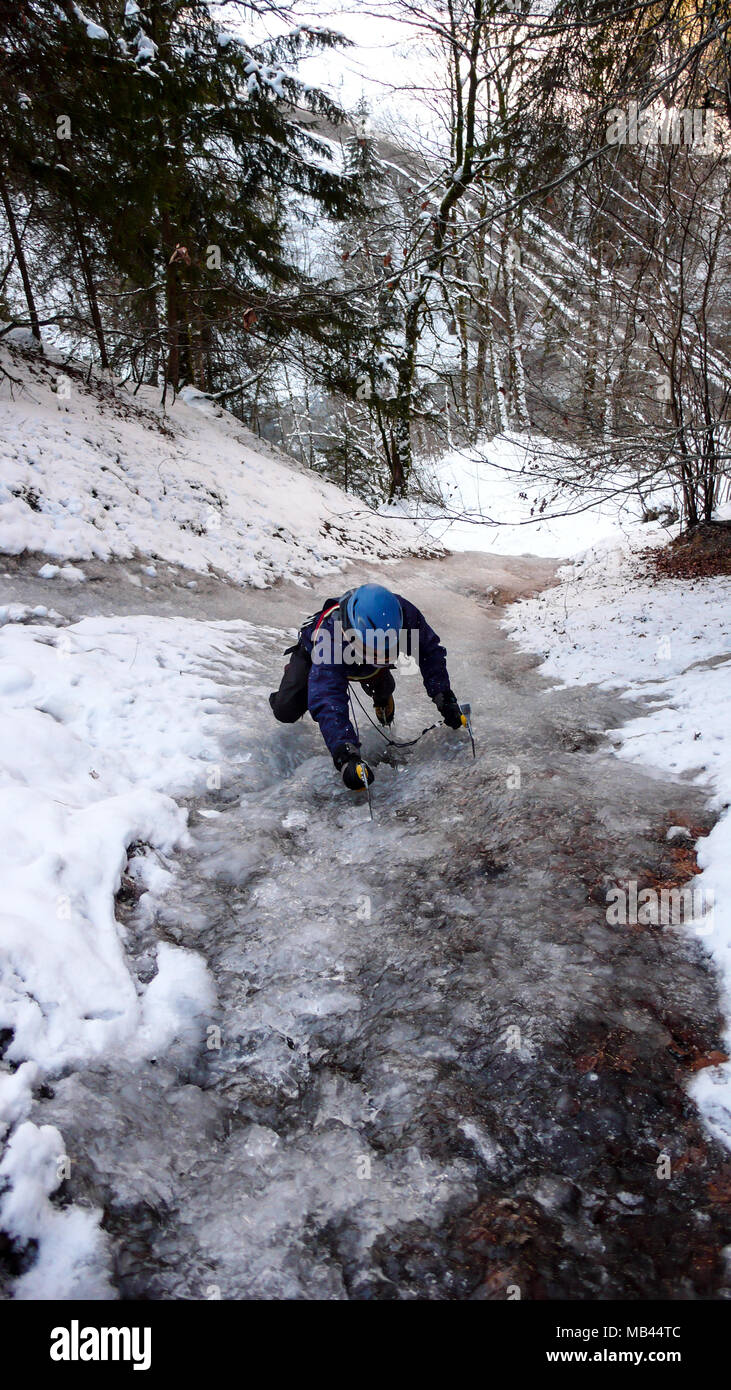 Männliche Eiskletterer free solo Klettern eine schmale eingefroren und steilen Bach im Winter Forest Stockfoto