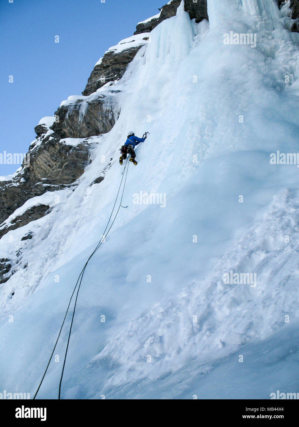 Männliche Eiskletterer führen Klettern auf einem steilen Wasserfall in den Schweizer Alpen in der Nähe von Davos. Stockfoto