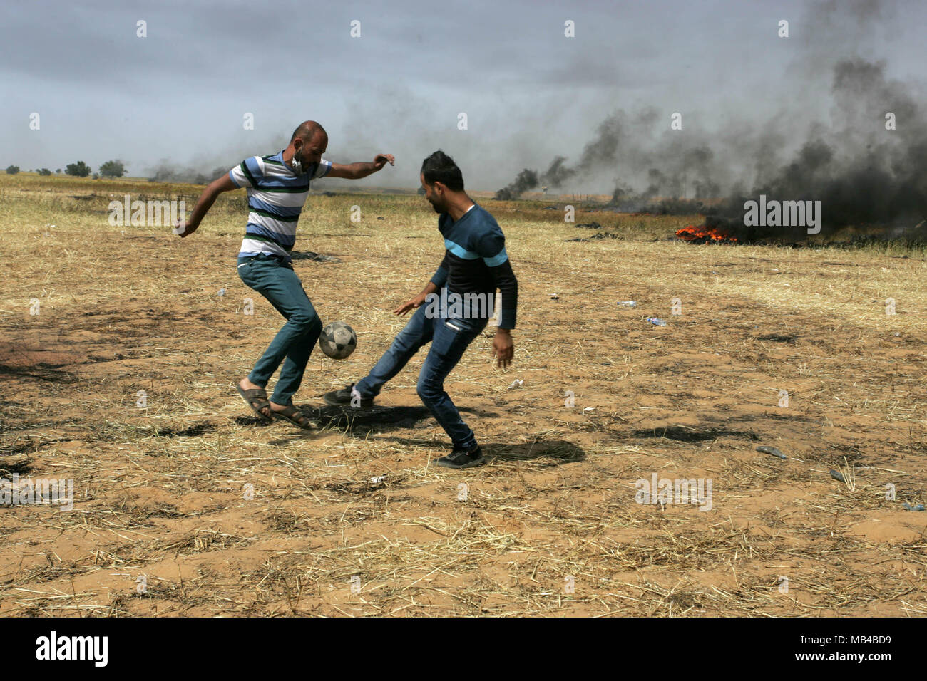 Gaza, Palästina. 6 Apr, 2018. Palästinensische Jugendliche spielen Fußball, während der Auseinandersetzungen mit der israelischen Sicherheitskräfte auf der Gaza-Israel Grenze nach einem Protest, östlich von Khan Yunis im südlichen Gazastreifen am 6. April 2018. Auseinandersetzungen ausgebrochen auf der Gaza-Israel Grenze eine Woche nach ähnlichen Demonstrationen zu Gewalt in die israelische Gewalt getötet 19 Palästinenser, die blutigste Tag seit einem Krieg 2014 führte. Credit: Erwachen Foto Agentur/Alamy leben Nachrichten Stockfoto