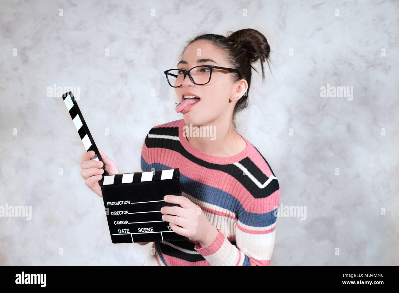 Junge Frau Schauspielerin comedy Funny Face Ausdruck Mund öffnen Mit Movie clapper board Grimasse Stockfoto