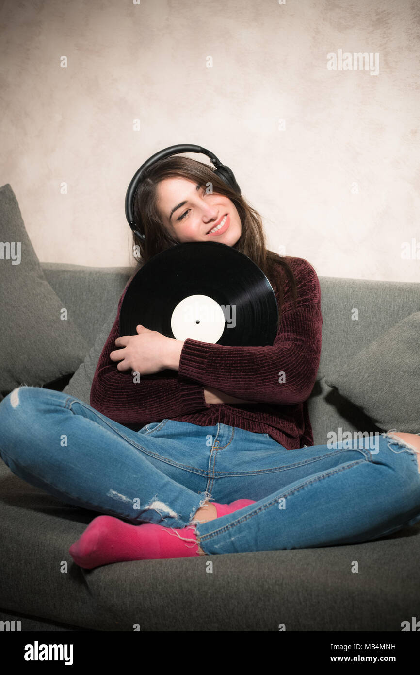 Attraktive junge Frau istening Musik mit Kopfhörer holding Schallplatte in den Armen Stockfoto