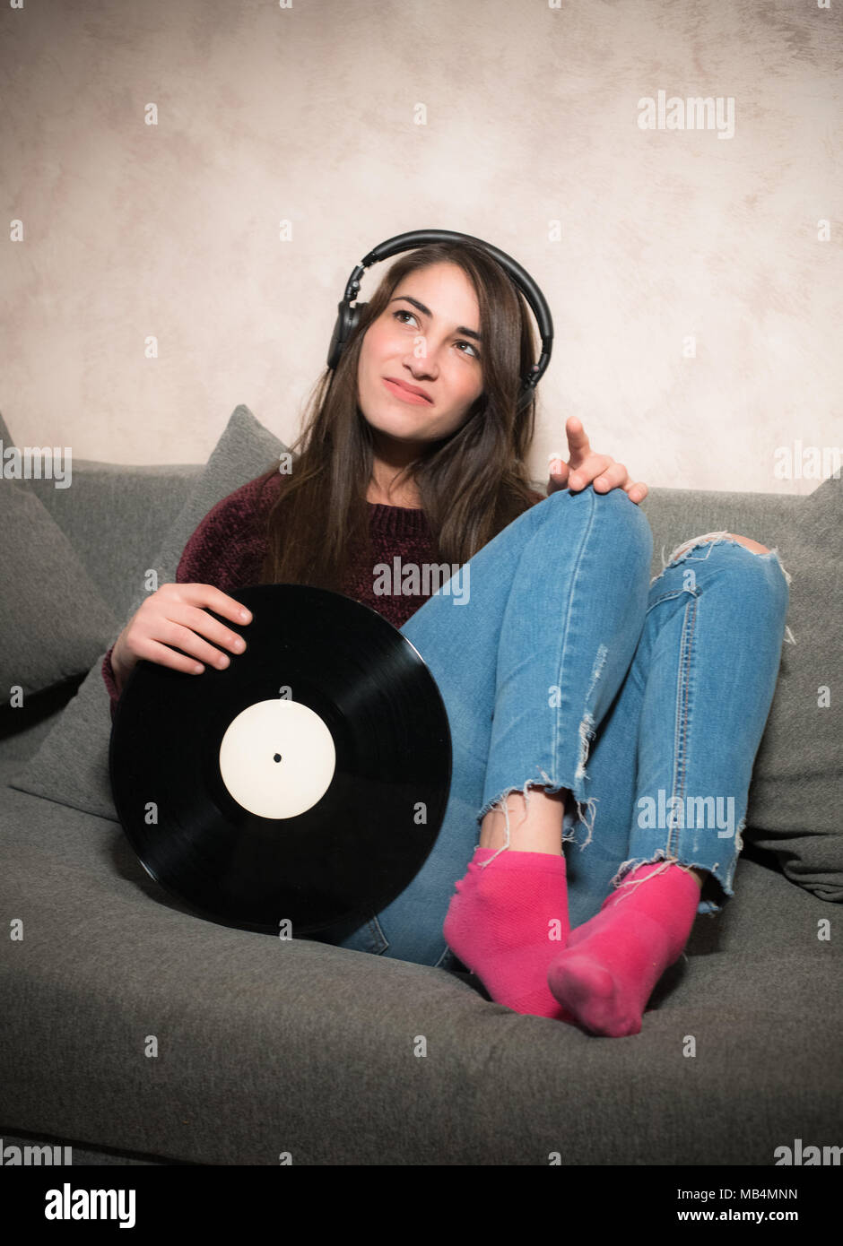Attraktive junge Frau istening Musik mit Kopfhörer holding Schallplatte in den Armen Stockfoto