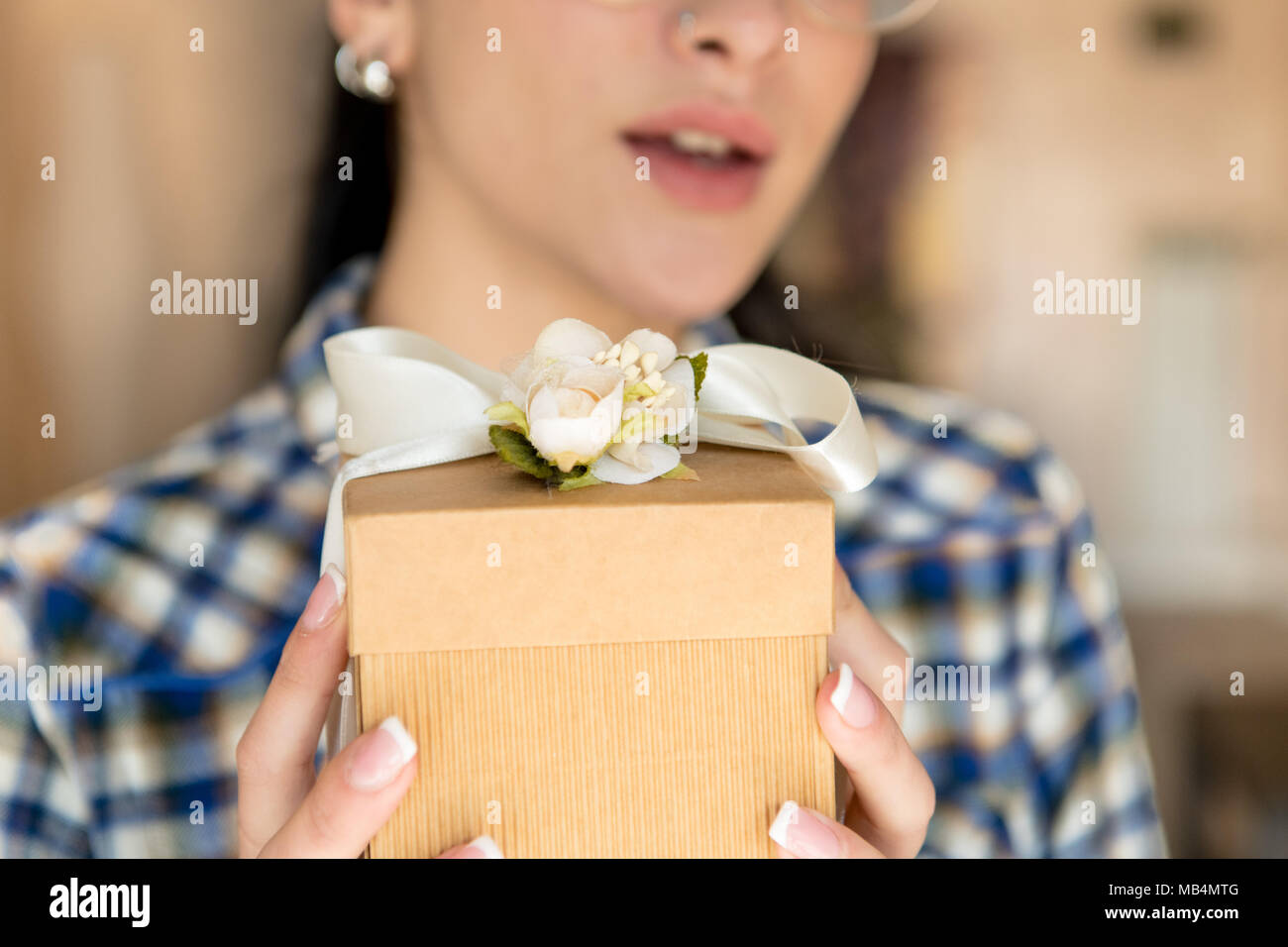 Frau Hände halten Geschenkbox menschliches Gesicht unscharf im Hintergrund Stockfoto
