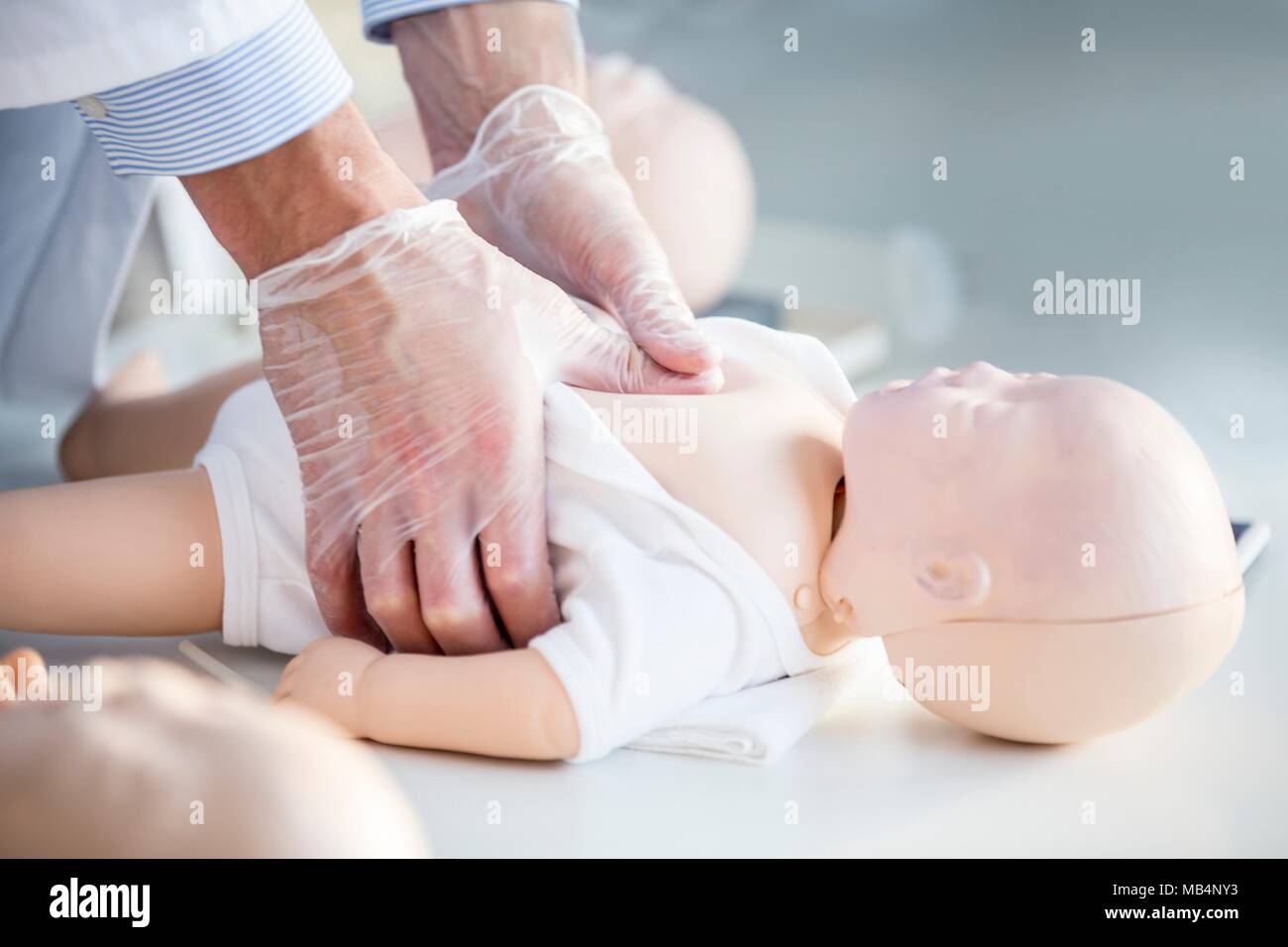 Der Doktor, der die Herzdruckmassage auf ein Kleinkind HLW Training dummy. Stockfoto