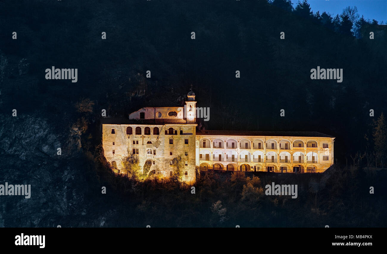 Heiligtum von Saint Lucia, teilweise in eine felsige Höhle, klammerte sich an der Seite des Mount Kalvarienberg, in der Nacht beleuchtet. Villanova Mondovì, Piemont. Stockfoto