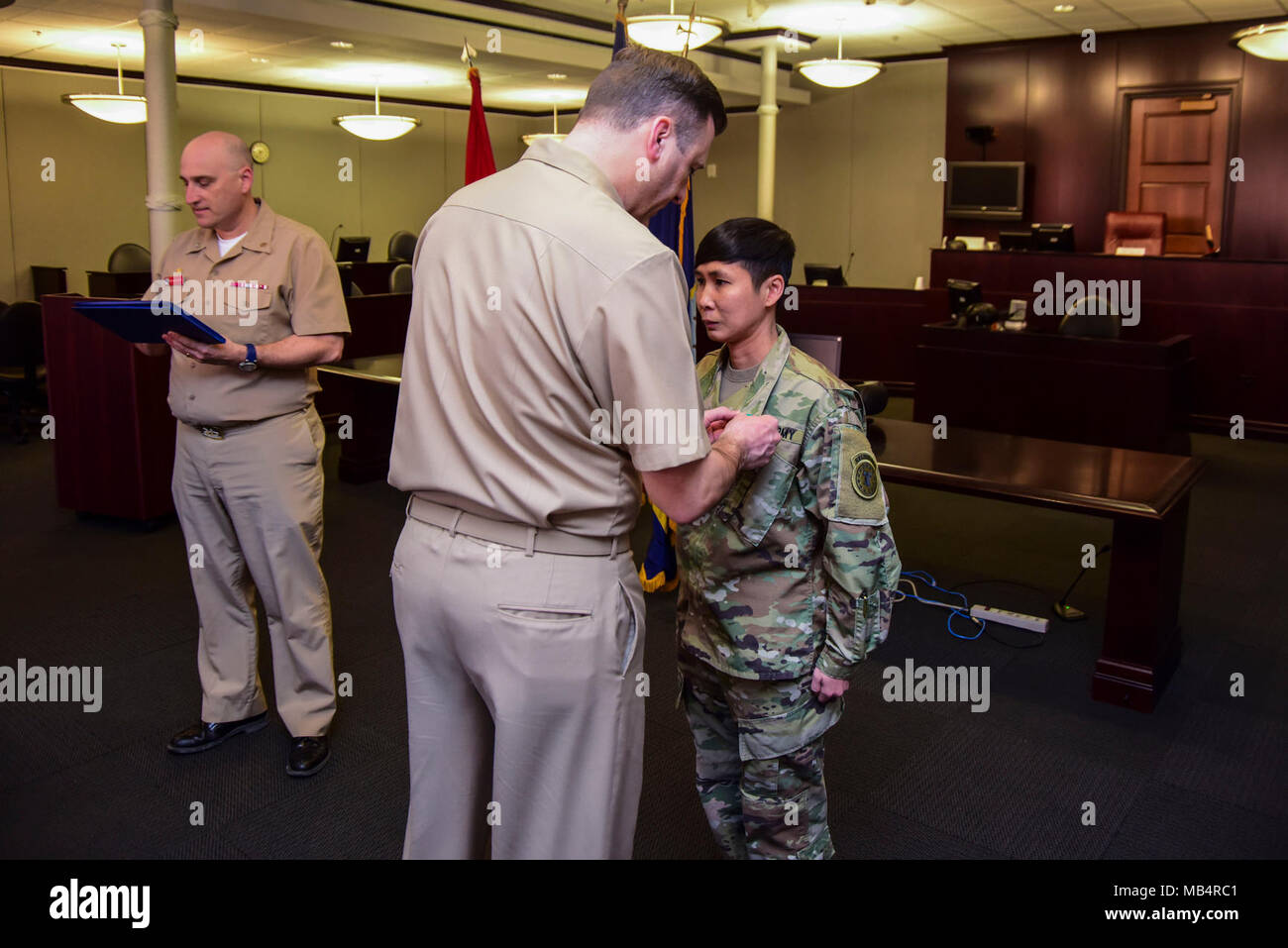 GREAT LAKES, Illinois (Feb. 14, 2018) Naval Station befehlshabenden Offizier, Kapitän James Hawkins (links) Auszeichnungen ein Navy und Marine Corps Leistung Medaille zu Army Staff Sgt. Jordan Siddhidhatashakti auf eine Preisverleihung statt innen Region Legal Service Office (RLSO) Mittelwesten, Gbd. 2, 24.02.14. Am frühen Morgen des Sept. 21, 2017, Siddhidhatashakti, zusammen mit MWR Great Lakes Mitarbeiter John Anderson, führten CPR auf RLSO Executive Officer Cmdr. Sarah sah Stancanti Stancanti, nachdem Sie von einem Laufband im Inneren der Gebäude fallen. 2 ein Fitnessstudio. Siddhidhatashakti und Anderson verwendet Teamarbeit während der CPR, wie Siddhidhat Stockfoto