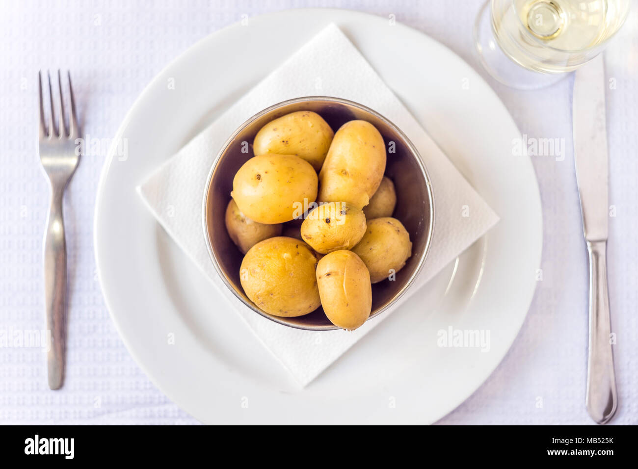 Gekochte baby Kartoffeln in Silber Schale mit Besteck und Weißwein, gedeckter Tisch Stockfoto
