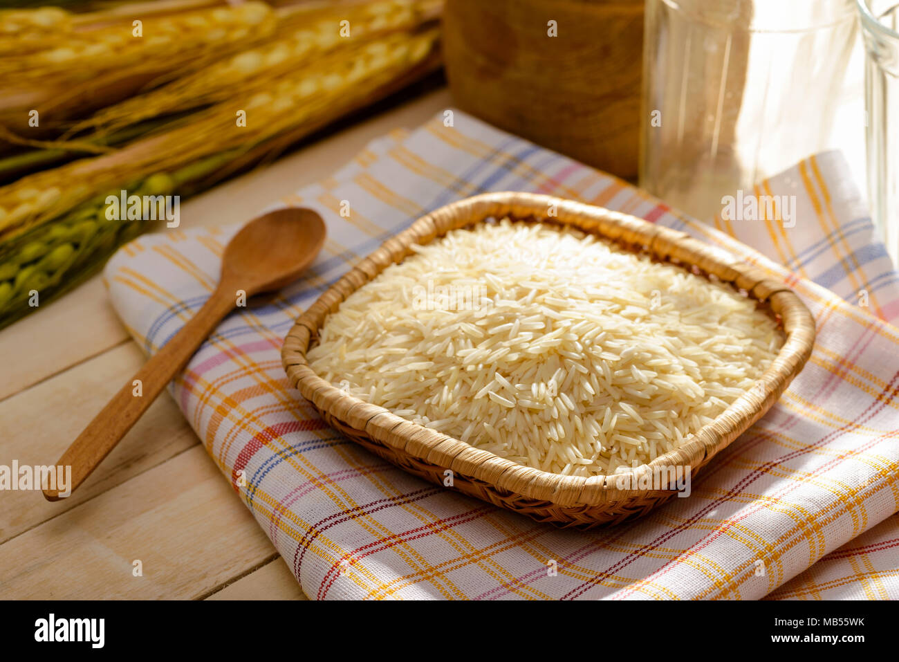Ungekochter Reis Basmati, extra lange Ausführung, in einem kleinen Teller auf einem Handtuch auf einen hölzernen Tisch. Basmati Reis ist ein grundlegender Bestandteil für viele asiatische Oriental Stockfoto