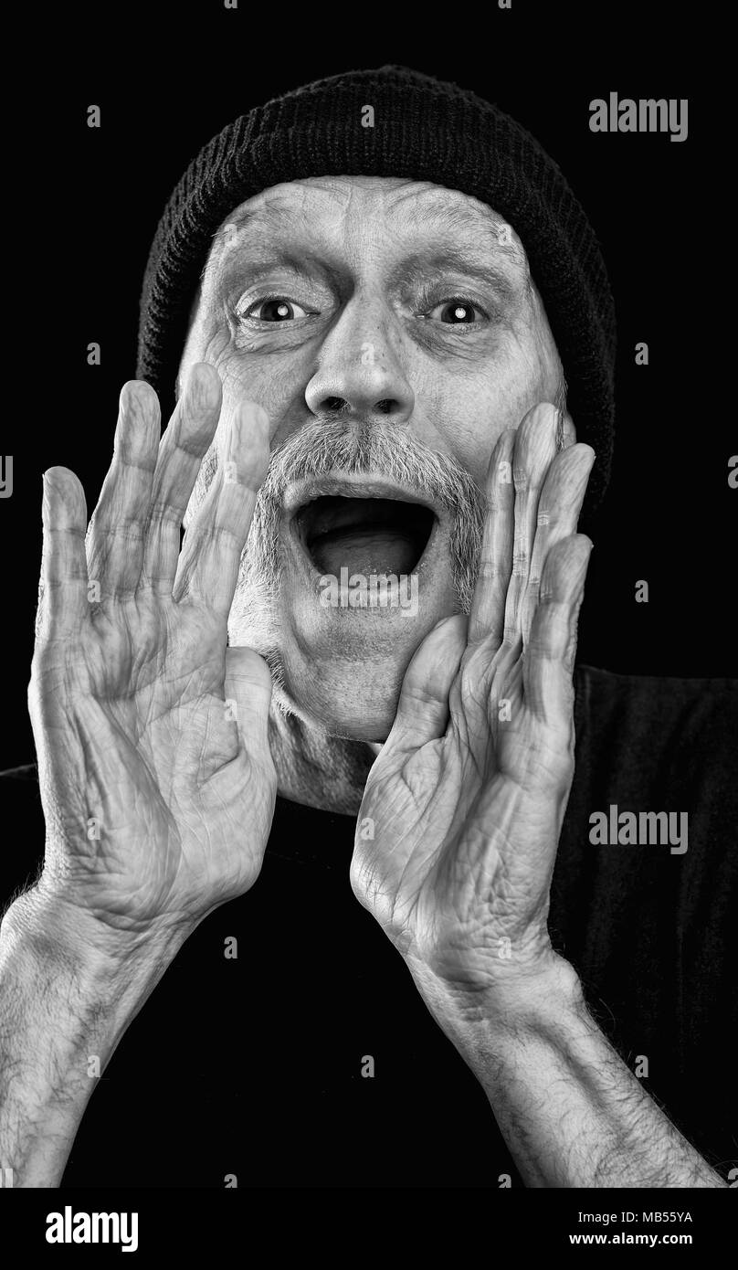 Dramatische schwarz-weiß Foto von einem starken Mann mit Bart mit einer Wollmütze auf dem Kopf, laut schreien, mit den Händen in ein Megaphon Geste Stockfoto