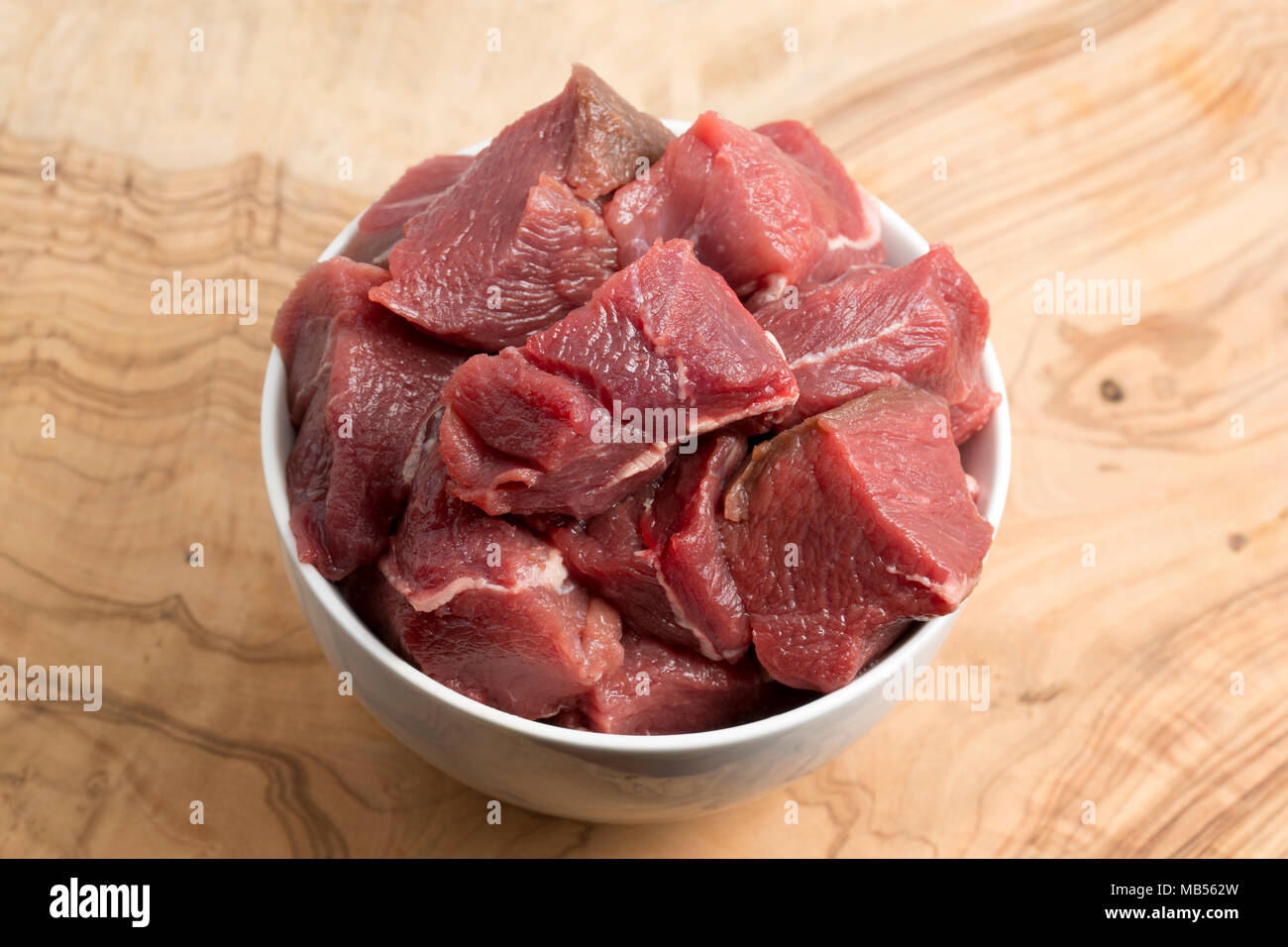 Gewürfelte rohe Schulter Fleisch von einem Wildschwein, Sus scrofa, von einem Wildschwein geschossen in der Toskana, Italien, vor dem Kochen. Auf einem weißen Hintergrund. Das Fleisch ist viel dar Stockfoto