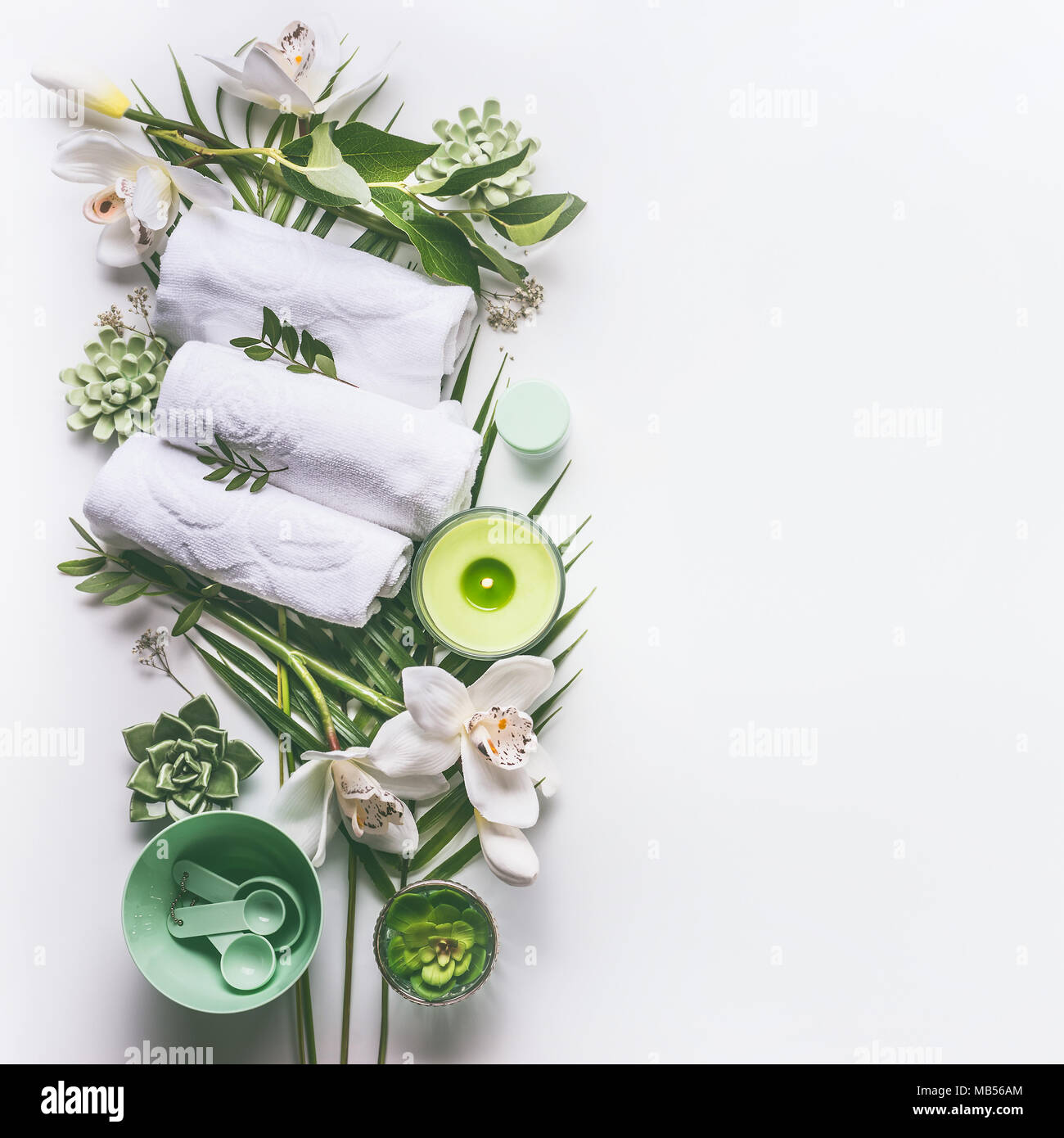 Green Spa Wellness oder Hintergrund mit Handtüchern, Kerze, tropische Blätter, Orchideen, Sukkulenten und Körper und Gesichtspflege Werkzeuge und Zubehör auf whi Stockfoto