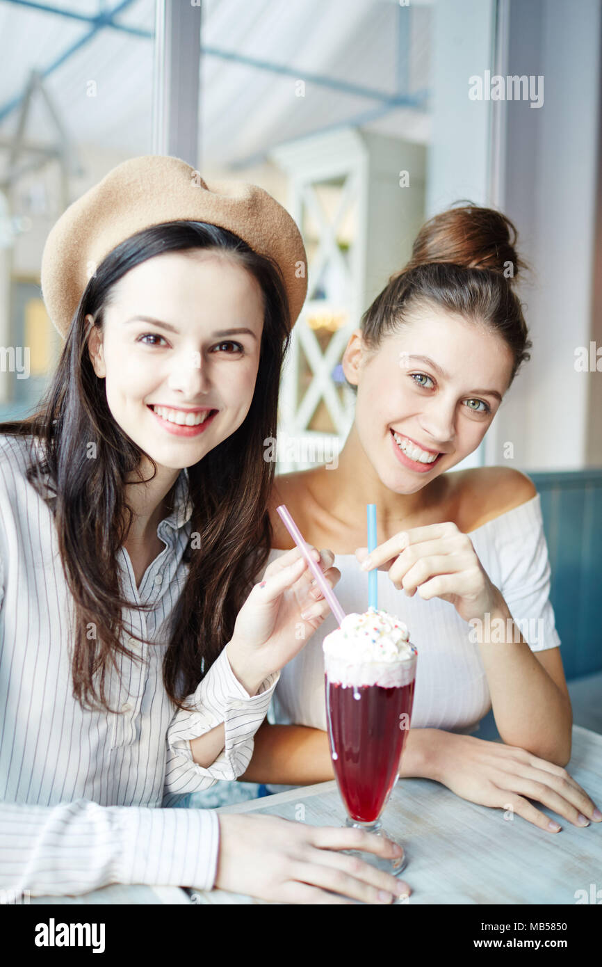Zwei hübsche Mädchen teilen leckeren Cocktail und genießen Sie die Zeit im Café am Wochenende oder zwischen den Klassen in der Hochschule Stockfoto
