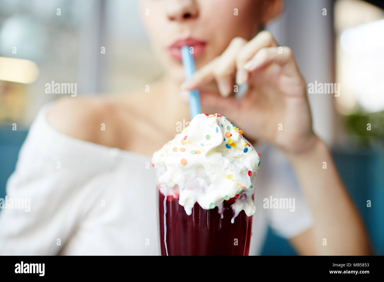 Glamouröse Mädchen trinken leckere Cocktail mit Eis bestreut oben durch Stroh beim Entspannen im Cafe Stockfoto