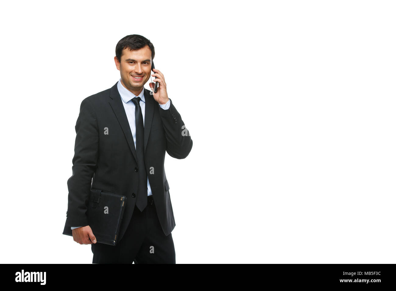 Hübscher junger Geschäftsmann in Business sut, blaues Hemd und Krawatte holding Tablet in Ledertasche. glücklichen Ausdruck. Jemand Gruß. Studio shot iso Stockfoto