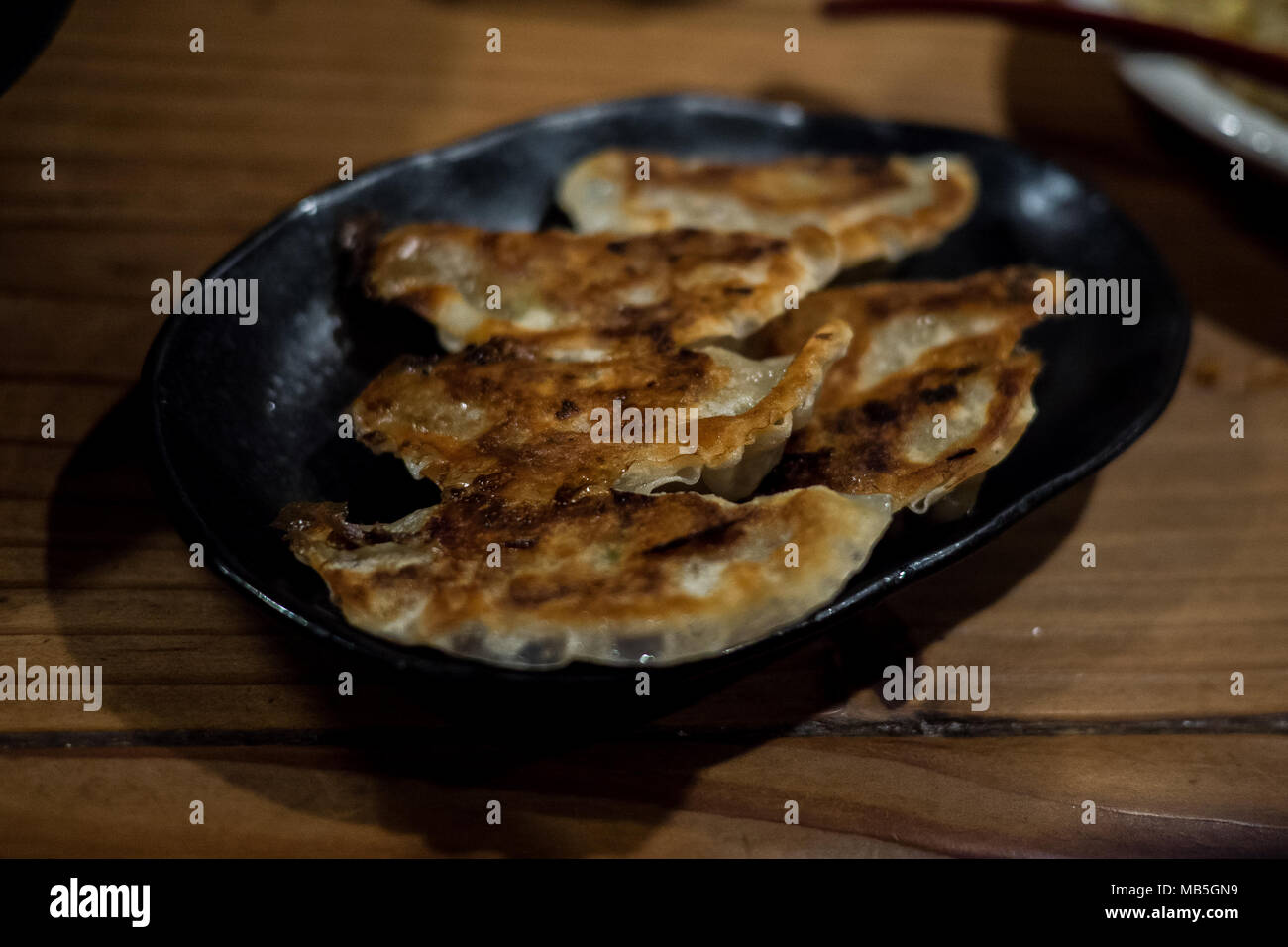 Gebratene gyoza ordentlich serviert auf einer schwarzen Platte auch als japanische Knödel Stockfoto