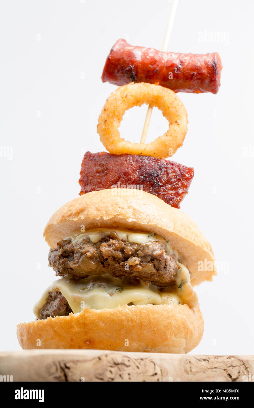Eine doppelte Wildschwein Burger aus einem Wildschwein geschossen in der Toskana, Italien, mit cambozola Käse und mit Chorizo Wurst und frittierten Zwiebeln garniert r Stockfoto