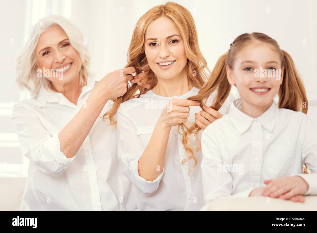 Strahlende Familie Frauen Mitglieder Haare flechten zusammen Stockfoto