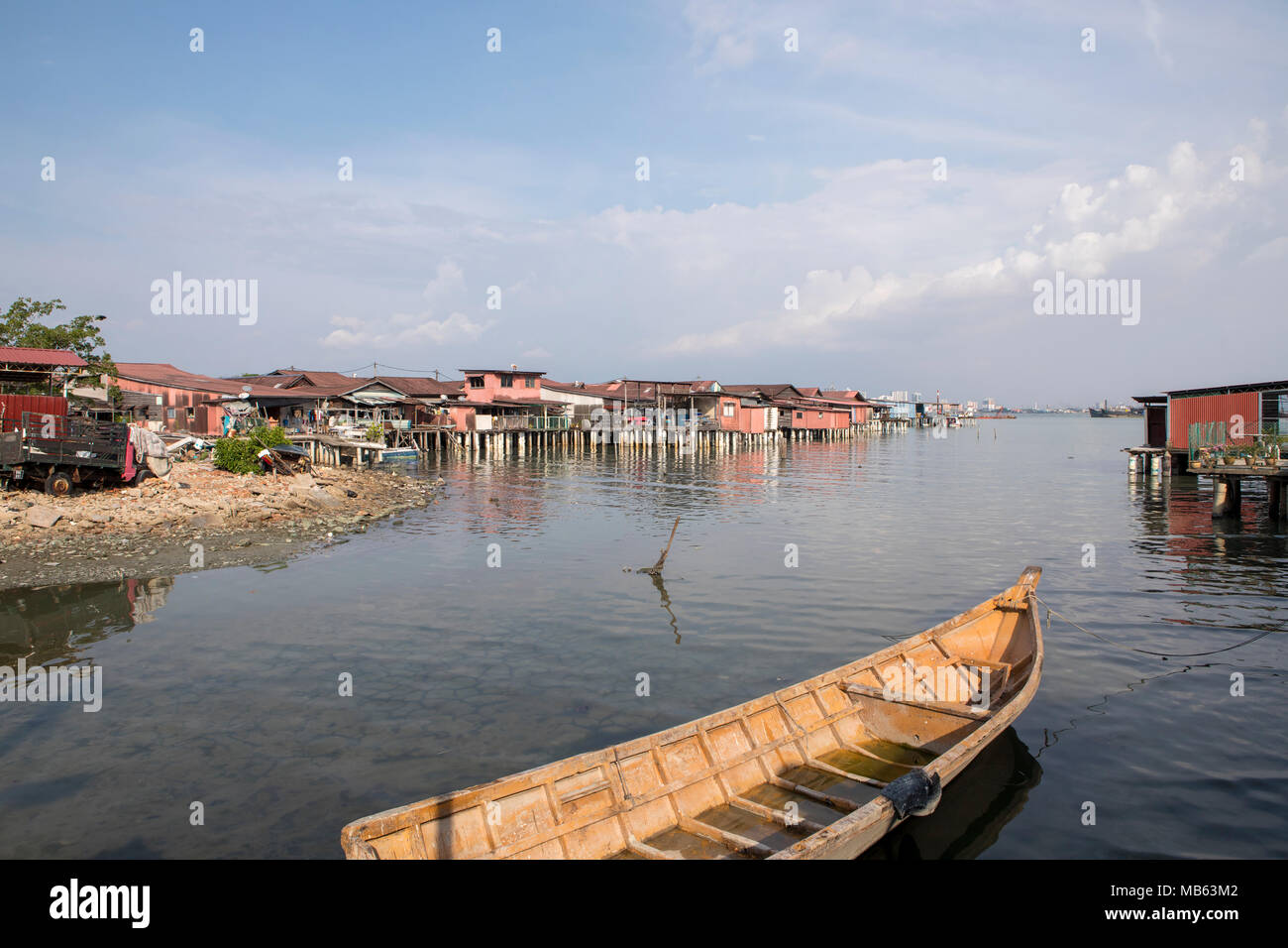 Noch Wasser durch die Clan Steganlagen in Georgetown Penang. Traditionelles hölzernes Boot in eine Ansicht der rustikalen Häusern auf Stelzen montiert. Stockfoto