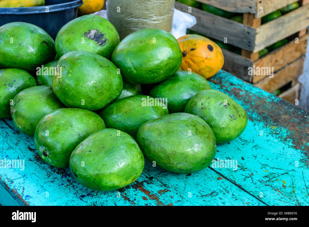 Stapel der grüne Mangos auf Türkis Tisch am Straßenrand stall in Guatemala, Mittelamerika Stockfoto