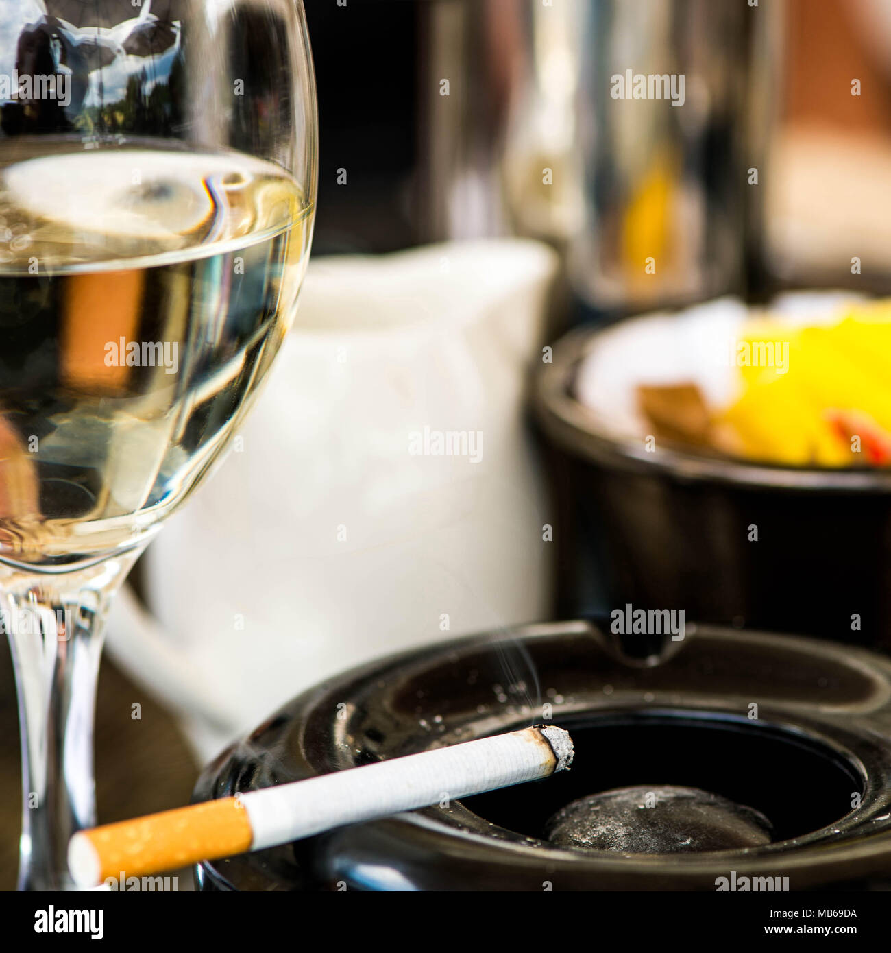 Zigarette in einem Aschenbecher mit einem Glas Weißwein Stockfoto